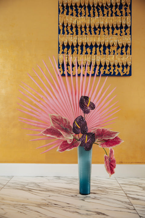 Exotische kunstbloemen van Odette Flowers met felle roze stengels en dieppaarse anthuriums in een gestructureerde turquoise vaas