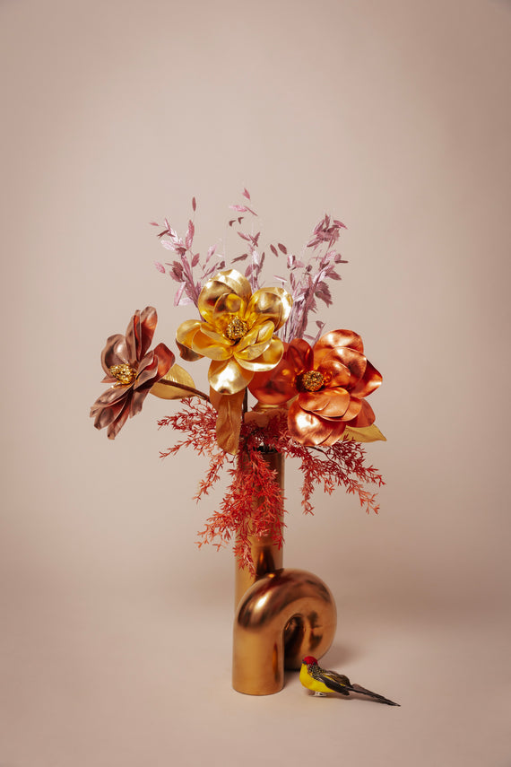 Odette's exclusieve boeket van goud- en kopertint kunstbloemen, sierlijk gepresenteerd in een moderne gouden vaas, een kunstzinnige toevoeging aan elke luxe interieurdecoratie