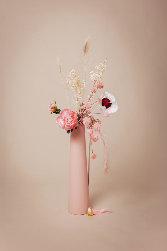 Odette's selectie van luxe kunstbloemen, waaronder roze rozen en crèmekleurige pluimen, in een stijlvolle pastelroze vaas voor een duurzame en onderhoudsvrije bloemdecoratie